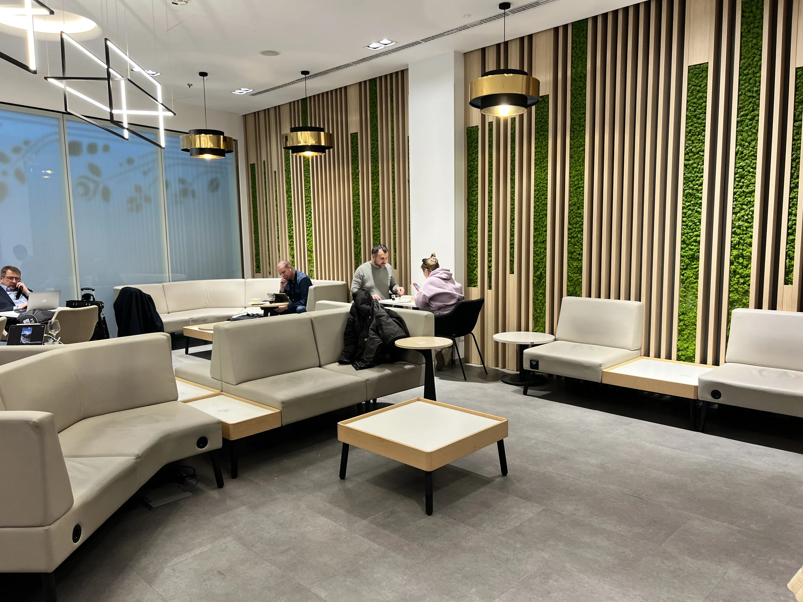 Cream sofas and seating area with green plant wall inside SkyCourt Lounge Budapest